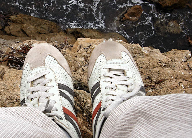 Person seated at very edge of cliff with feet dangling over precipice