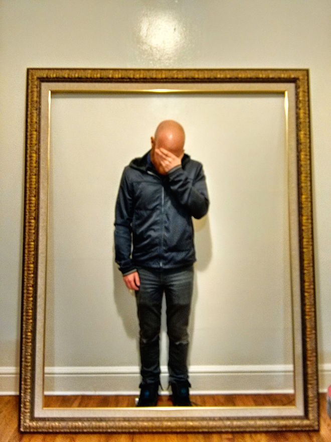 Photograph of a man facepalming himself surrounded by a gilded frame