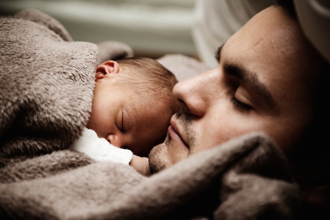 Photo of baby cuddling with father.