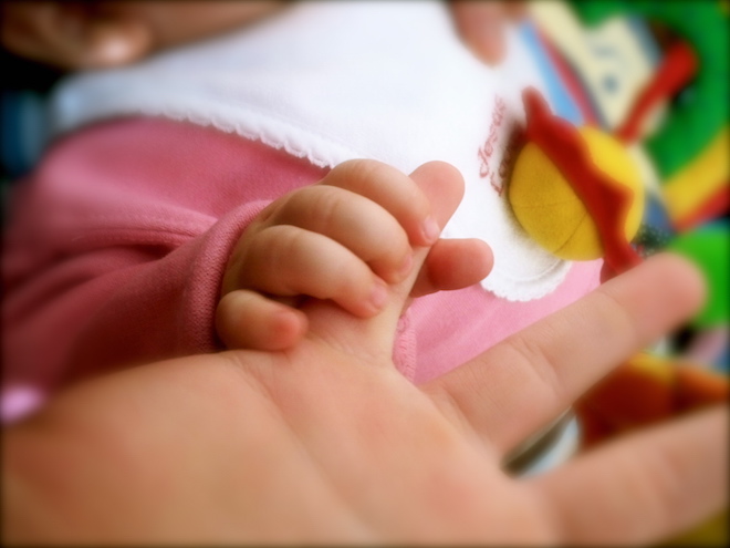 Photo of child's hand grasping an adult's hand