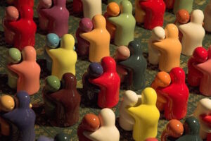 Mutli colored ceramic figures hugging one another.