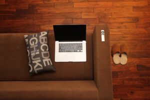 At home with a laptop on a couch with cushion and slippers.