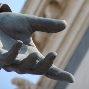 Photo of the hand of a statue extended, palm up, as if in offering.