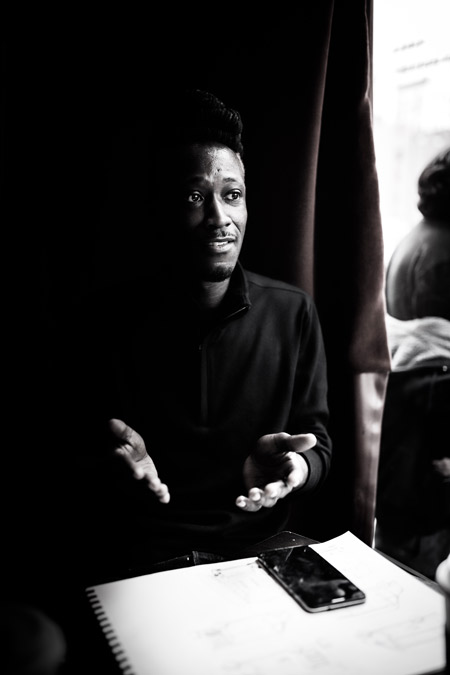 A man speaking to someone in a cafe.