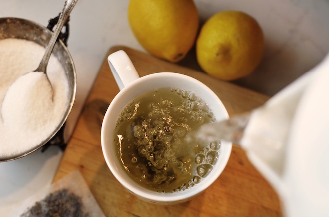 Image of tea being poured with sugar and lemons available.