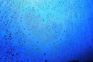 A heart etched out on a window covered in water droplets