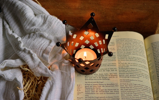 A bible with a baby cloth and candle in a crown