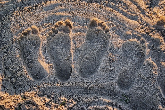 Two sets of footprints in the sand, side-by-side.