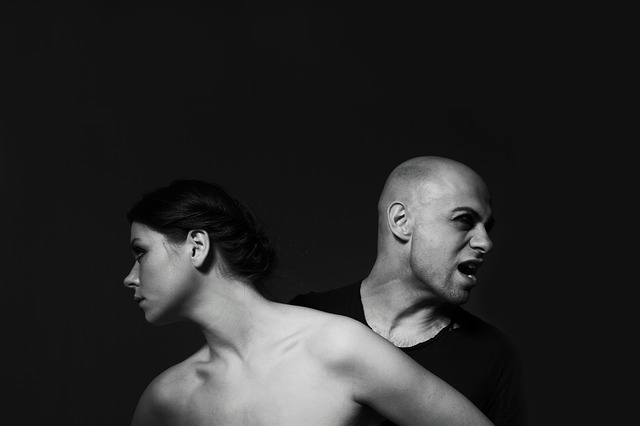 A black and white photo of two people stretching in opposite directions, one with a neutral expression, the other looking fiercely aside.