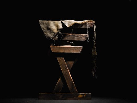A simple manger constructed of wood with torn cloth.
