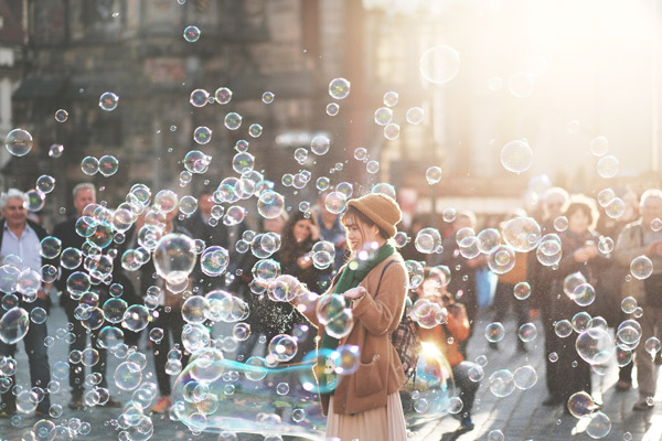 A person surrounded by people, sharing the experience of many floating bubbles.