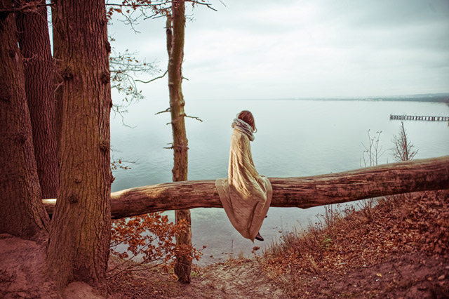 A woman sitting in solitude by a lake.