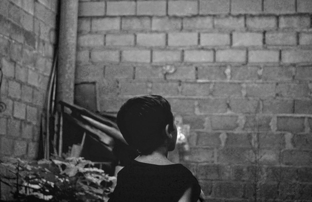 A little boy facing a wall.