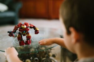 A young boy looking at an Iron Man toy on a table