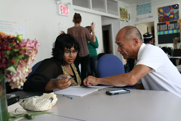 A man helping a woman fill out a form
